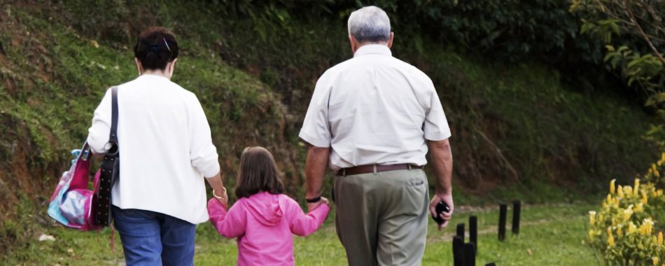 grandparents holding hands with child, walking away from camera