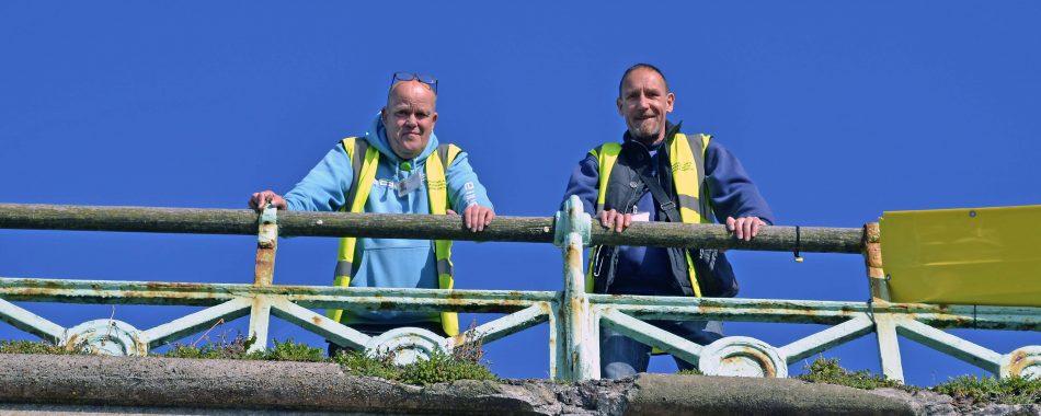Two men stood at the top of the promenade in Brighton, looking down.