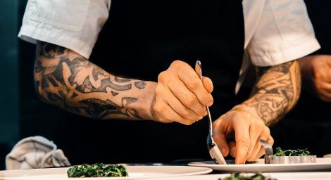 Photo of man with tattoos working in restaurant kitchen
