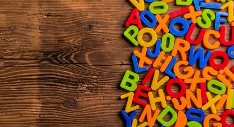 A brightly coloured pile of letters lies on top of a wooden surface.